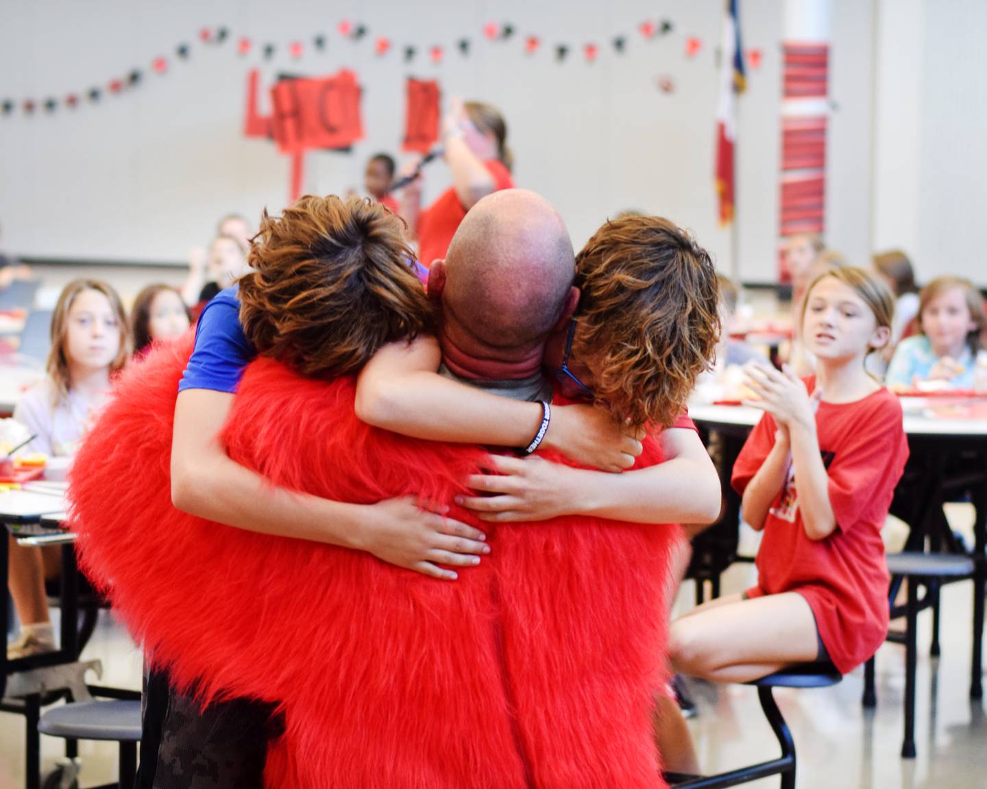 Brothers Sam Richards, 11, and Jaiden Richards, 12, embrace their dad, Cody Richards, after finding out he was disguised as Big Red and thus has returned home from a deployment overseas.