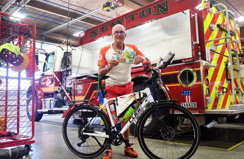 Jörg Richter, a German cyclist and former firefighter, shows off a notebook with the map of his route from San Francisco to New York. Richter made an overnight stay at the Newton Fire Department. He is riding to bring awareness to children with rare diseases.