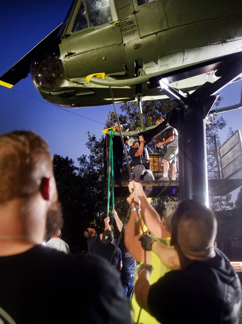 Crews attach anchors to the Huey helicopter monument while other volunteers keep it steady on Sept. 30 in Baxter.