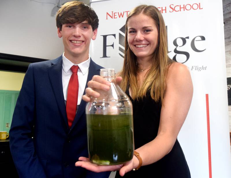 From left: Seniors Treycen Garton, 18, and Kallie Van Kley, 17, show off an algae solution after a presentation May 17 inside the Fledge classroom of Newton High School.