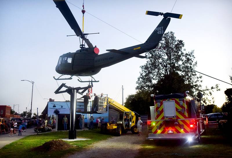 Dave's Crane & Wrecker Service help lower the Huey helicopter onto its raised platform on Sept. 30 in Baxter.