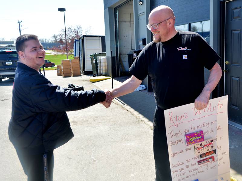 Ryan Dannen of Ryan's Tire & Auto, right, shakes hands with Newton High School student Maynard Meling after accepting a thank you card for his business's $3,000 donation to The Big Game.