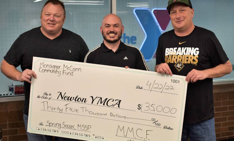 From left: Mark Thayer, Lucas Hughes and Scott Taylor pose for a picture with the Monsignor McCann Community Fund grant awarded to the Newton YMCA for the 2023 spring soccer season and the middle school sports program, which will let all participating kids to play at no cost to their families.