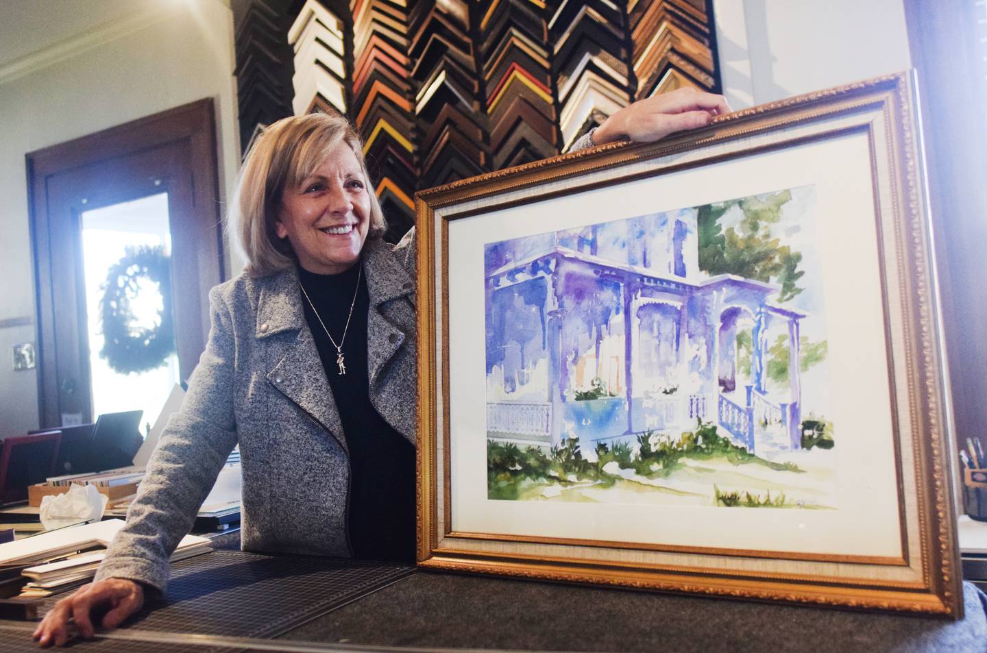 Pauli Zmolek Eades, owner of Cardinal Frame Shop, shows off one of her paintings framed in an ornate frame. The shop opened for business this past week to appointments, but it also welcomes walk-in traffic.