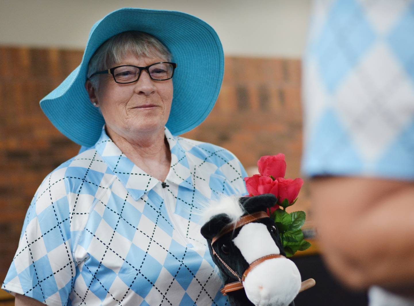 Lana Wohlers, co-president of board of directors at Newton Arboretum & Botanical Gardens, wears Kentucky Derby attire and gallops on a toy horse after speaking with city council members on April 21 about the upcoming spring plant sale.