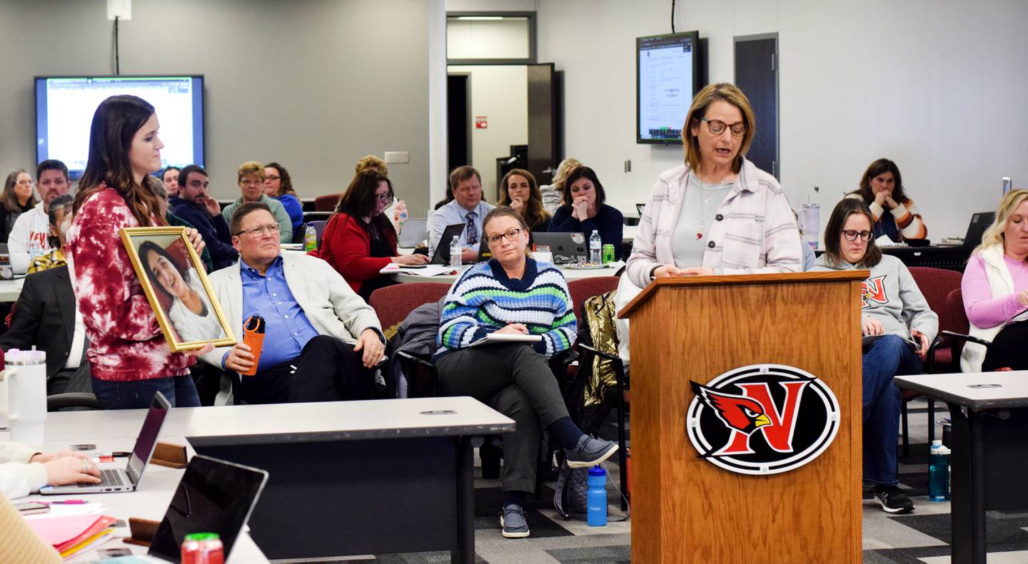 Lora Caves, right, a second grade teacher at Aurora Heights Elementary School, speaks to board members about the importance of AEA and how it helped her daughter Meredith, whose picture is being held by Taylor McDonnell, a school counselor at Aurora Heights Elementary School. Meredith Caves, who had Rett Syndrome, died at age 29 in July 2022.