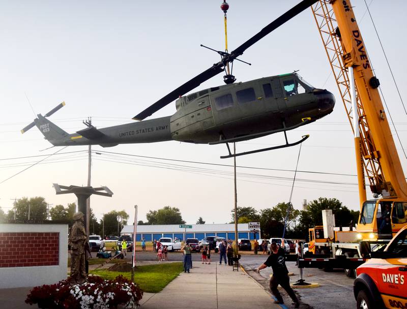 Crews from Midwest Aerospace and Dave's Crane & Wrecker Service help lift the Huey helicopter onto its raised platform on Sept. 30 in Baxter.