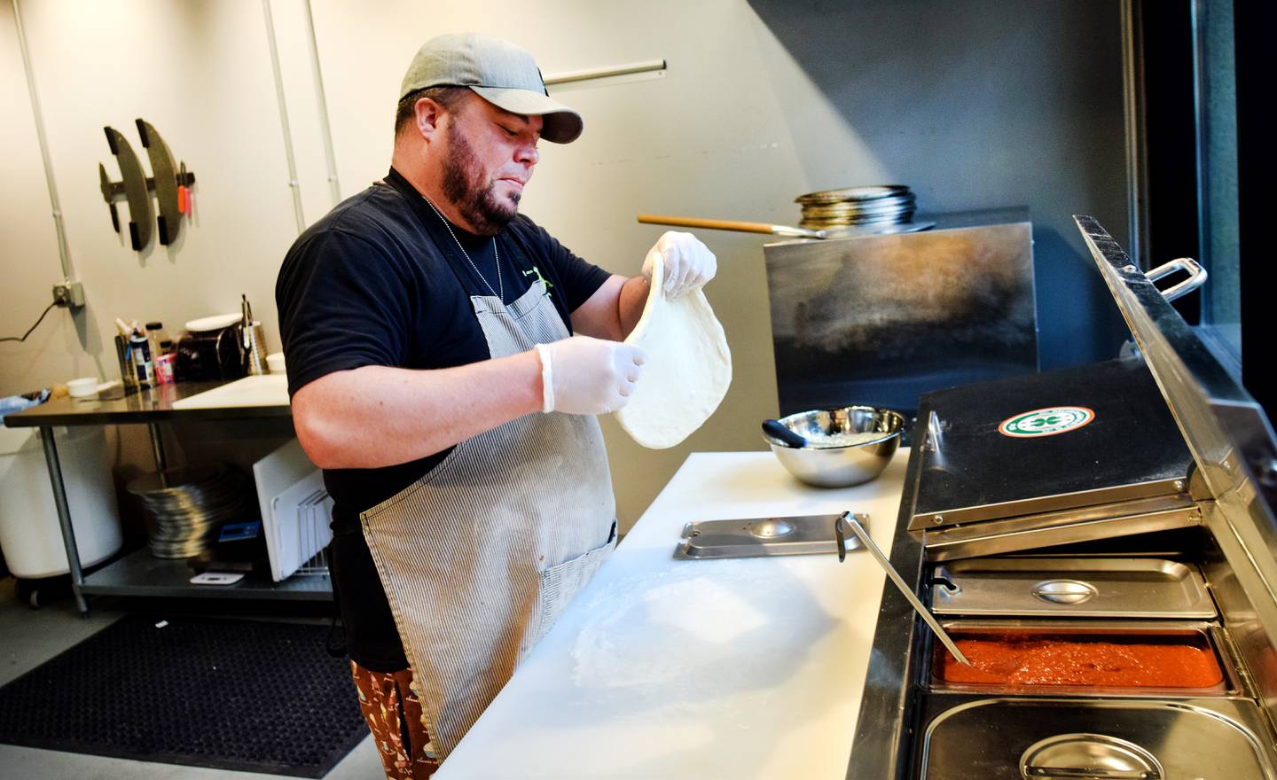 Conor Fudge, owner of Murph & Mary's Pub, prepares an order of garlic cheese bread inside the pizzeria kitchen of the Newton bar located in Legacy Plaza.