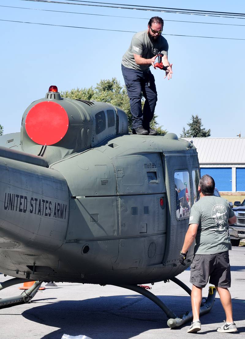 Joe Giannini of Midwest Aerospace passes Jeff Gembala a tool assemble the Huey helicopter that was put on display Sept. 30 in downtown Baxter.