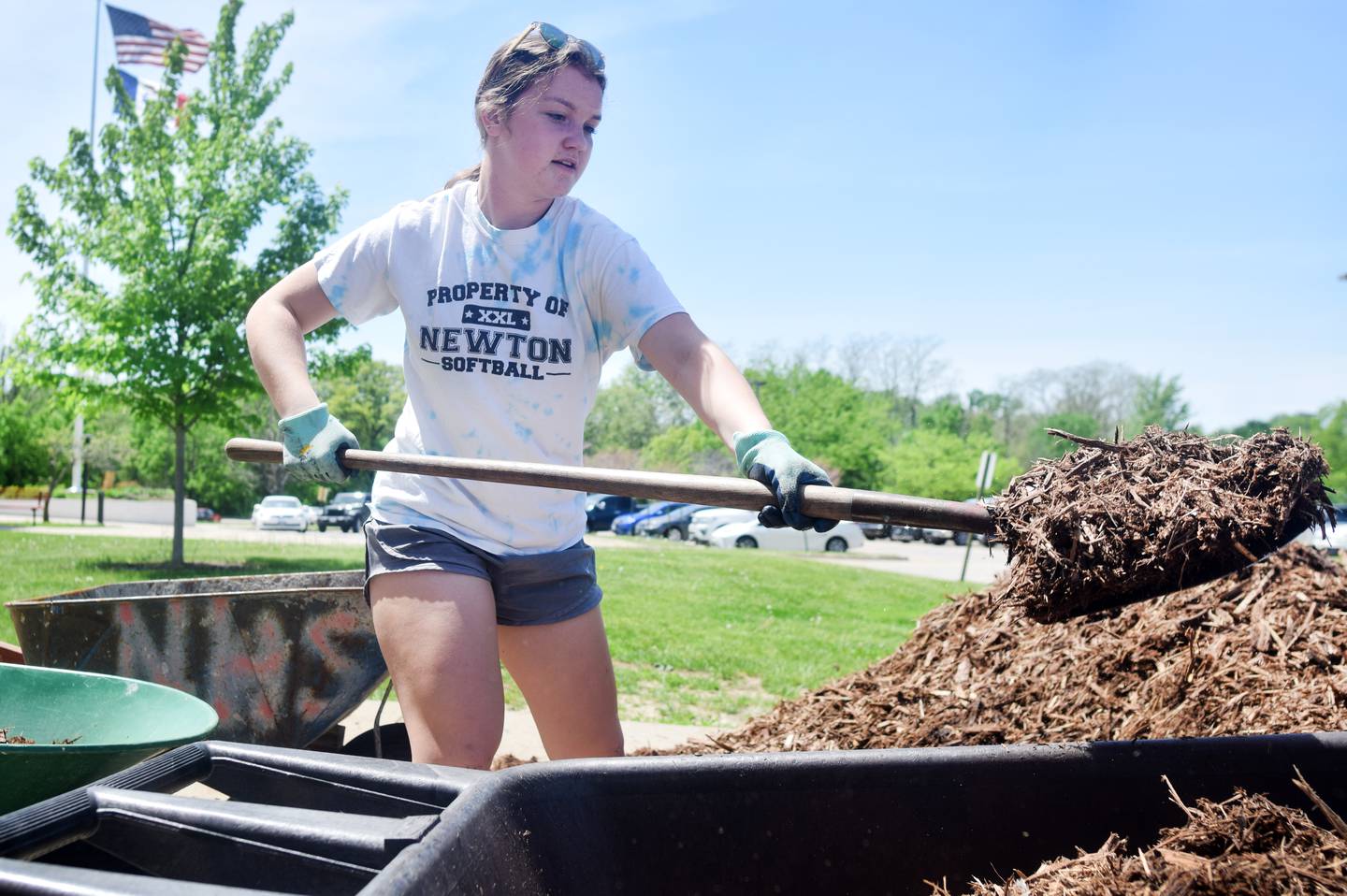 Emily Wermager, a junior, shovels mulch into a wheelbarrow May 19 outside Newton High School.