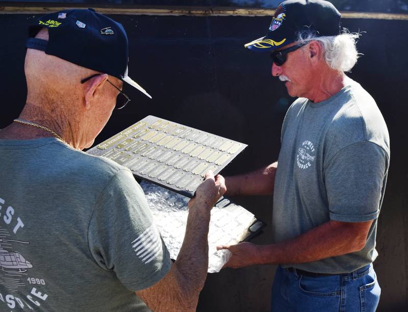 Lynn Harnden and Greg Christianson inspect the names of individuals and businesses who helped make the Huey helicopter memorial possible.