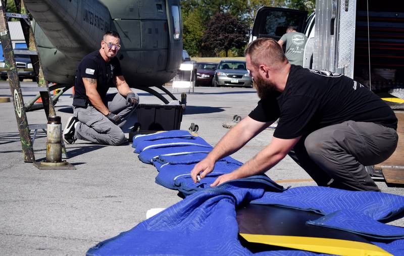 Luke Schreiber and JT Mullins of Midwest Aerospace unwrap the main rotor of the Huey helicopter.