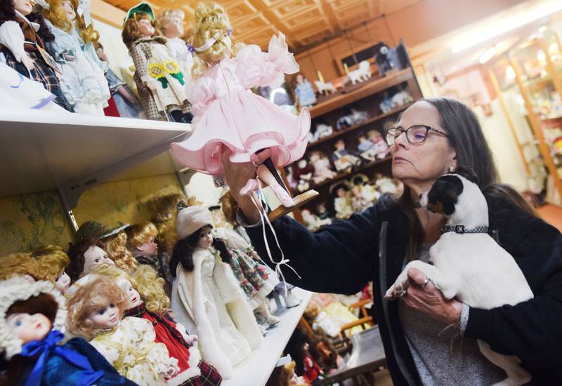 Laurie Nelson, owner of Relics LLC Antiques, Collectibles and Shtuff, inspects a ballerina doll inside the antique shop's doll room. The downtown retailer recently celebrated its 10-year anniversary, and while staff are thankful to see the shop stick around for so long they are also worried about the economy and the changing market.