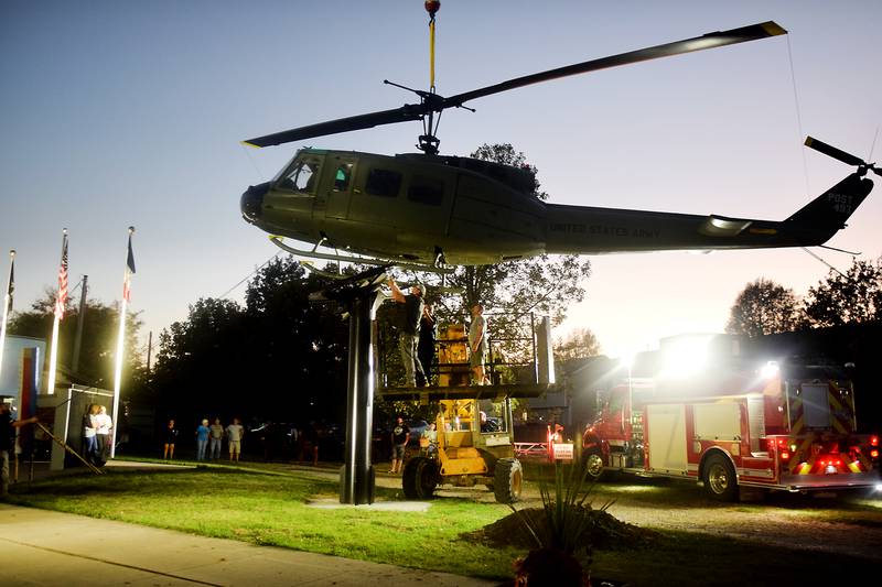 Dave's Crane & Wrecker Service help lower the Huey helicopter onto its raised platform on Sept. 30 in Baxter.