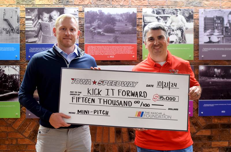 Eric Peterson, president of Iowa Speedway, presents a check to Brett Lundberg, right, for $15,000 to go towards the soccer mini-pitch project in Maytag Park.