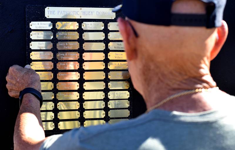 Lynn Harnden, a retired Lt. Colonel of the U.S. Army, sees his reflection on the aluminum name tags of those who donated to the Huey helicopter memorial.