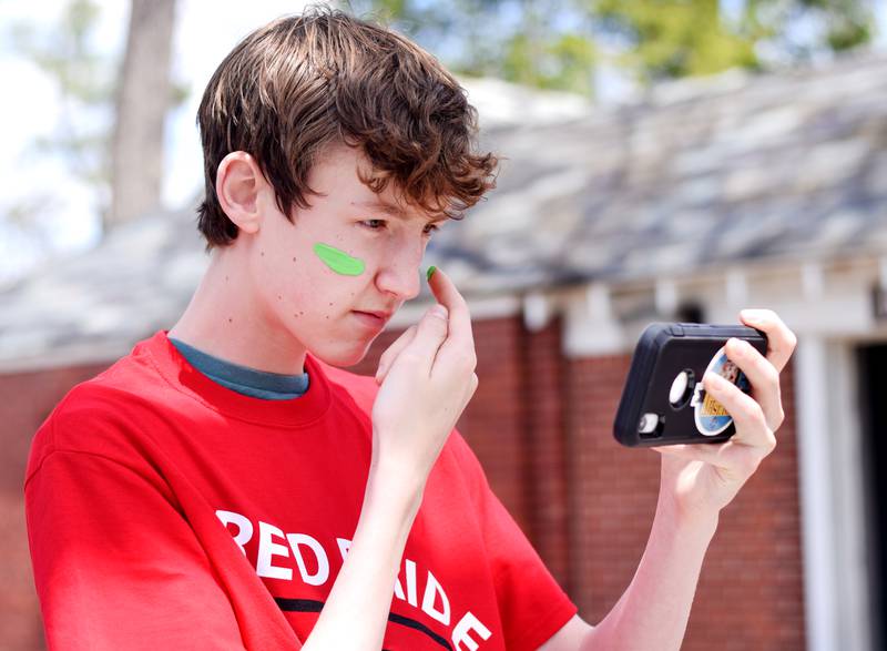 Newton students on May 4 paint their faces before painting Christmas light displays for the city's Maytag Park Holiday Lights during Red Pride Service Day.