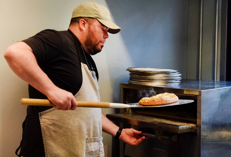 Conor Fudge, owner of Murph & Mary's Pub, pulls out a freshly baked serving of garlic cheese bread from the oven during opening day of the new pizza menu at the Newton-based bar.