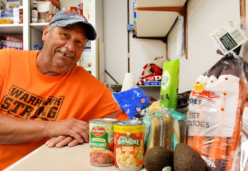 Ed Poe, food pantry coordinator for the Salvation Army in Newton, poses next to some of the food included in the Healthy Kids Iowa boxes distributed at the facility.