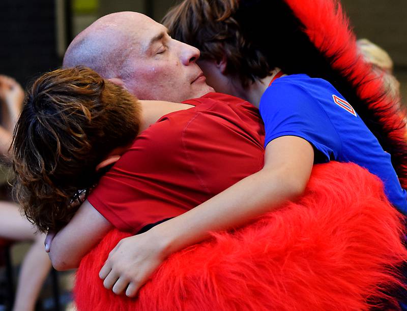 Cody Richards, a sergeant first class in the U.S. Army who just finished his fourth and final deployment, embraces his sons Jaiden, 12, and Sam, 11, after making a suprise visit to their school dressed as Big Red on Sept. 20 in Berg Middle School.