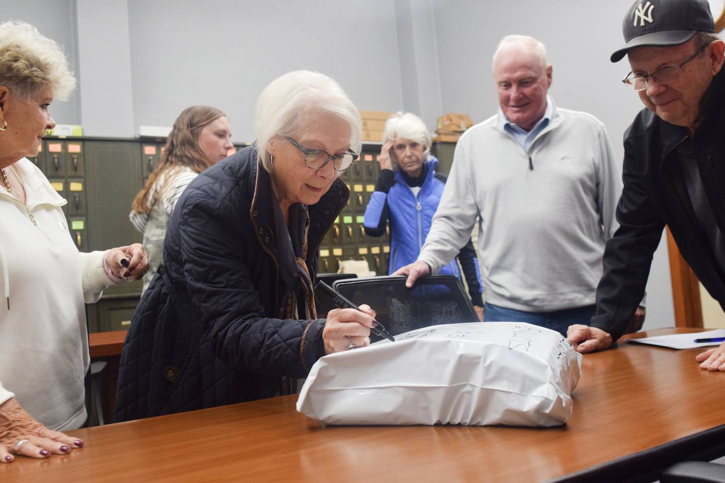 Volunteers sign their names on a sealed envelope containing the 600 absentee ballots counted during Election Day.