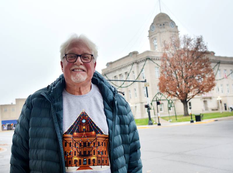Steve Knight, who fundraises for the Jasper County Courthouse Lighting, poses in front of the courthouse wearing a shirt showing what the structure looks like fully lit. Knight said a Los Angeles man who is also a Newton Cardinal donated $40,000 to the event, which went towards new garland, free-standing arches and trailer.