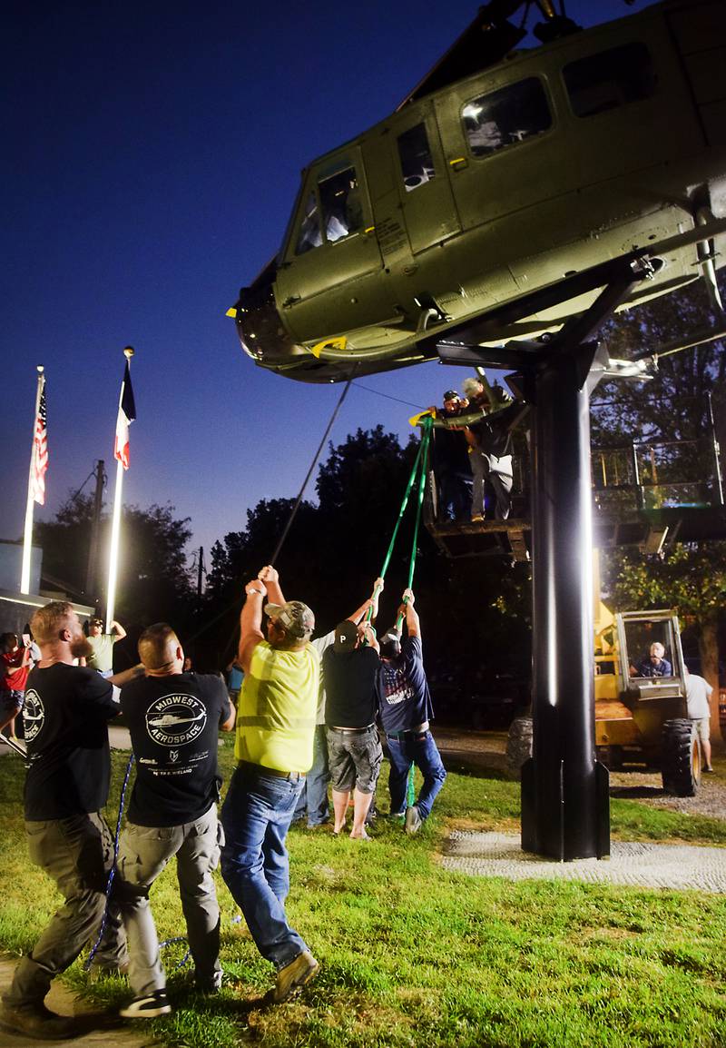 Crews tug at the Huey helicopter monument to get it into a better position to affix anchors on Sept. 30 in Baxter.