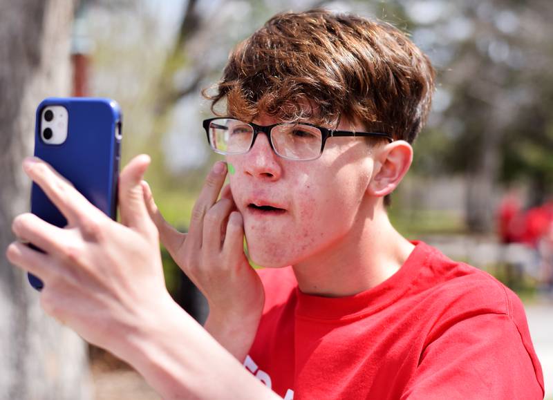 Newton students on May 4 paint their faces before painting Christmas light displays for the city's Maytag Park Holiday Lights during Red Pride Service Day.