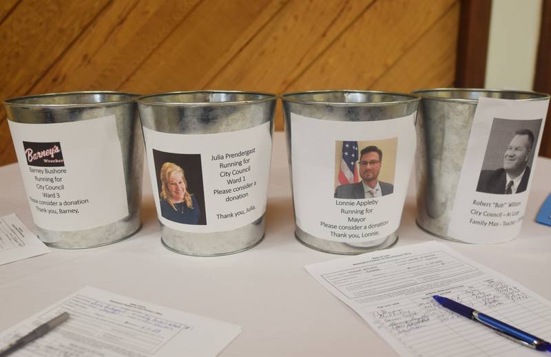 Donation buckets for city council and mayor candidates are displayed on a table during a private event by the Newton Business Council.