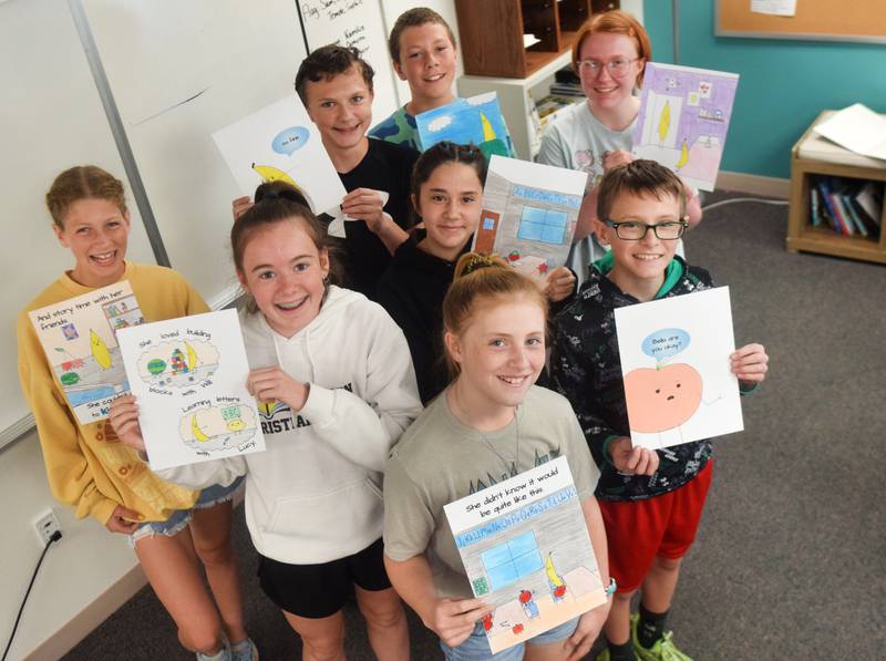 Middle school students of Jessica Moore's classroom in Newton Christian School show off the pages of their original children's book, which is going to be on display at the StoryWalk in Agnes Patterson Park.