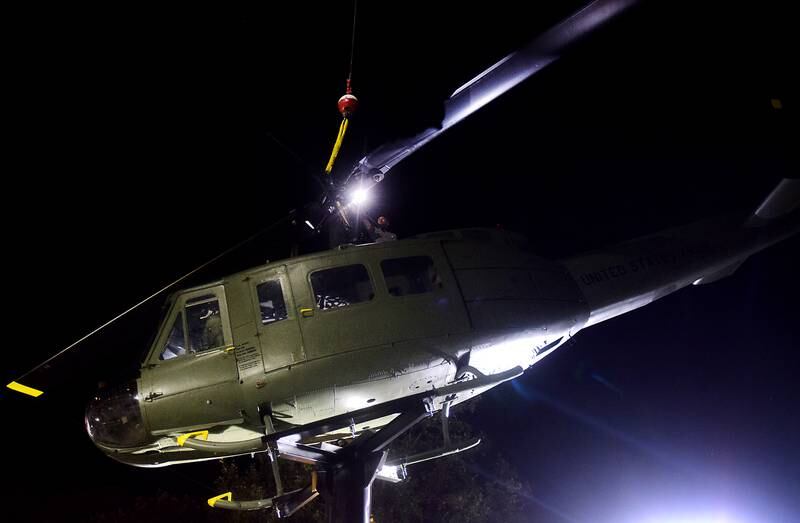 Crews remove crane hook from the Huey helicopter memorial after safely fastening to its raised platform on Sept. 30 in Baxter.