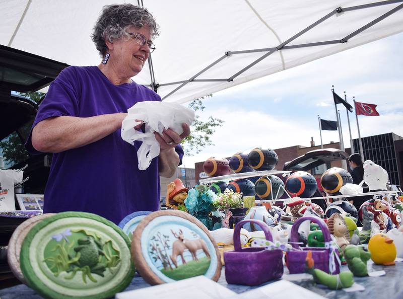 Sheryl Anderson of Grinnell wraps a sold item for a customer during the Newton Farmers Market on June 1, 2021, in the north side of the town square.
