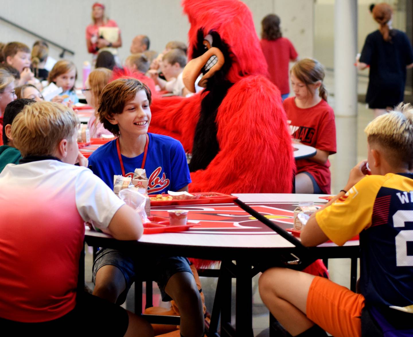 Sam Richards, 11, speaks with his friends at the lunch table, unaware that his dad, Cody Richards, is disguised as Big Red and waiting to surprise him and his brother, Jaiden, of his return home from a nine-month deployment in Romania for the U.S. Army.
