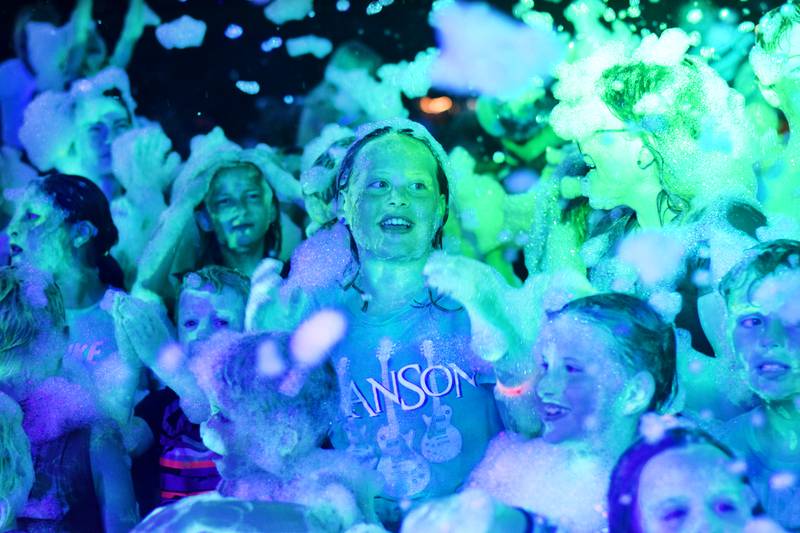 Kids participate in Driving Cap Entertainment's UV Glow Foam Party during Newton Fest on June 9 in Maytag Park in Newton.