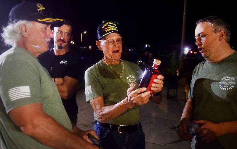 Lynn Harnden, a retired Lt. Colonel of the U.S. Army, reacts when receiving a commemorative bottle of whiskey from Joe Giannini of Midwest Aerospace, the company that supplied and assembled the Huey helicopter memorial.