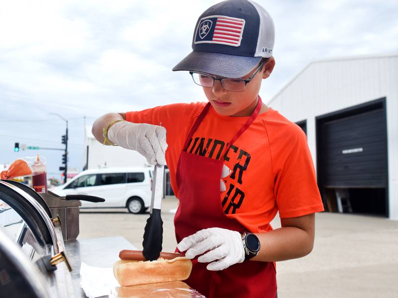 Harrison Miller, 12, prepares a Chicago-style hot dog on July 7 at Heavenly Hot Dogs, a hot dog cart just outside of Integrity Cleaning & Restoration in Newton.