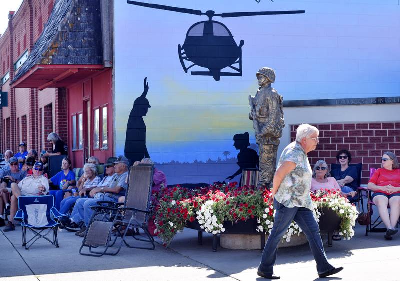 Onlookers stay under the shade to watch the progress of the Huey helicopter memorial on Sept. 30 in Baxter.
