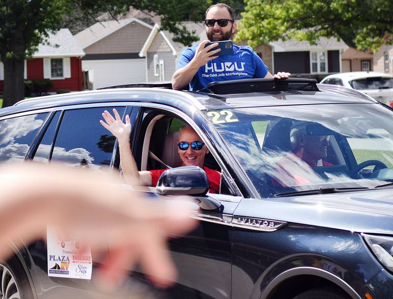 Hours before the downtown celebration of RVTV in Newton, Keith Murphy waves while Scott Siepker records from the sunroof during a mini-parade on Sept. 4 outside Berg Middle School.