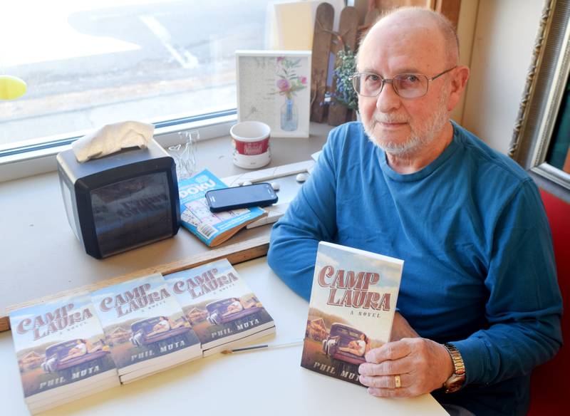 Phil Muta holds up a copy of his first book, "Camp Laura," during a signing March 27 at PJ's Deli. Muta founded the Newton-based deli 37 years ago and has since transferred ownership to his son and daughter-in-law. Doing so allowed Muta to finally tell a story he had wanted to write for almost 40 years, long before he owned the deli.