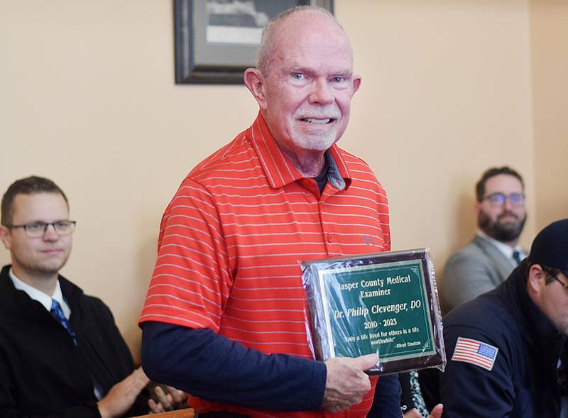 Dr. Phil Clevenger poses for a picture holding a plaque he received from Jasper County Sheriff John Halferty honoring him for his service as the county's longtime medical examiner.