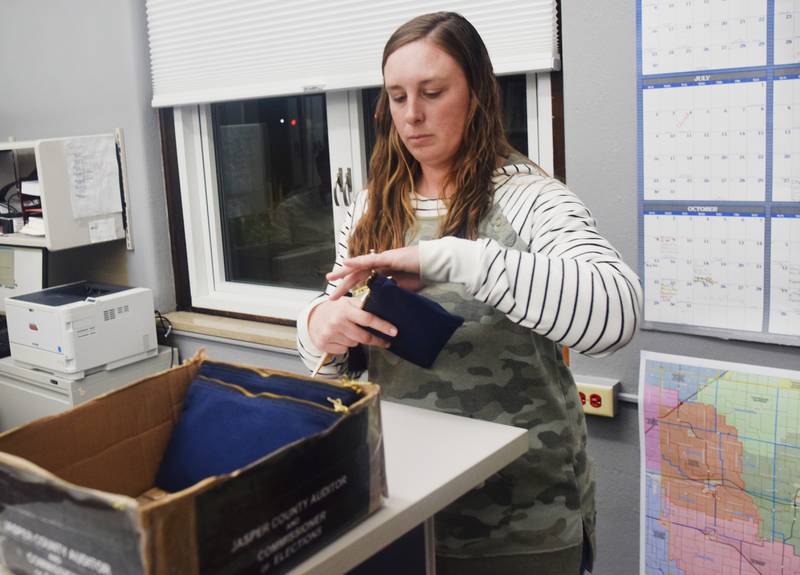 Jasper County Auditor Jenna Jennings seals a blue bag after downloading the Election Day poll data that was contained inside it.