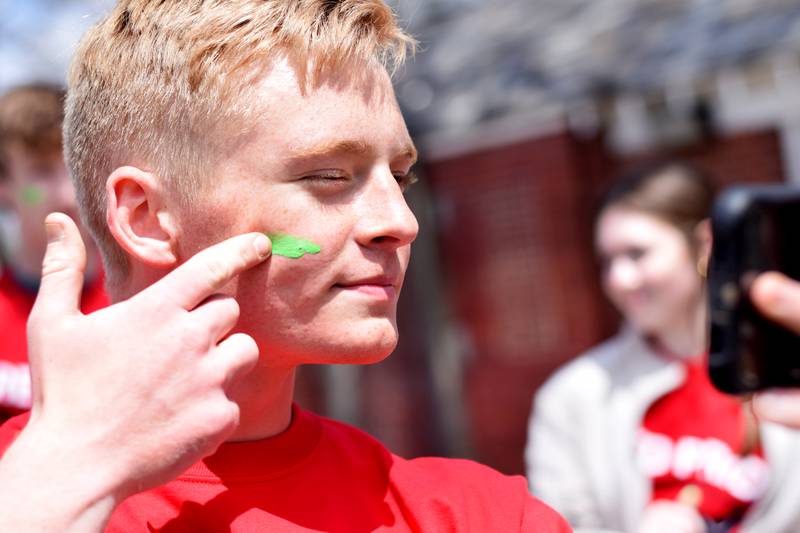 Newton students on May 4 paint their faces before painting Christmas light displays for the city's Maytag Park Holiday Lights during Red Pride Service Day.