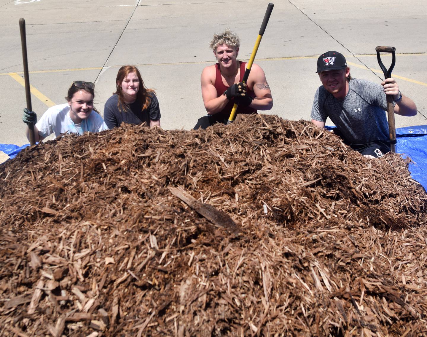 From left: Emily Wermager, Libby White, Zay Arguello and Braydon Chance pose for a picture May 19 with a pile of mulch for the courtyard garden of Newton High School.