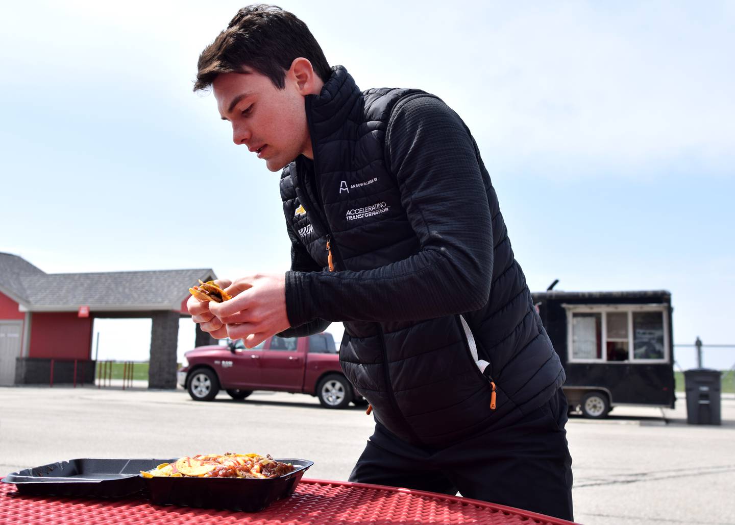 Professional race car driver Pato O'Ward tries a bite of the brisket nachos at Barrel Smoke BBQ & Catering during the Hy-Vee IndyCar Race Weekend's food truck challenge preview April 27 at Iowa Speedway in Newton.
