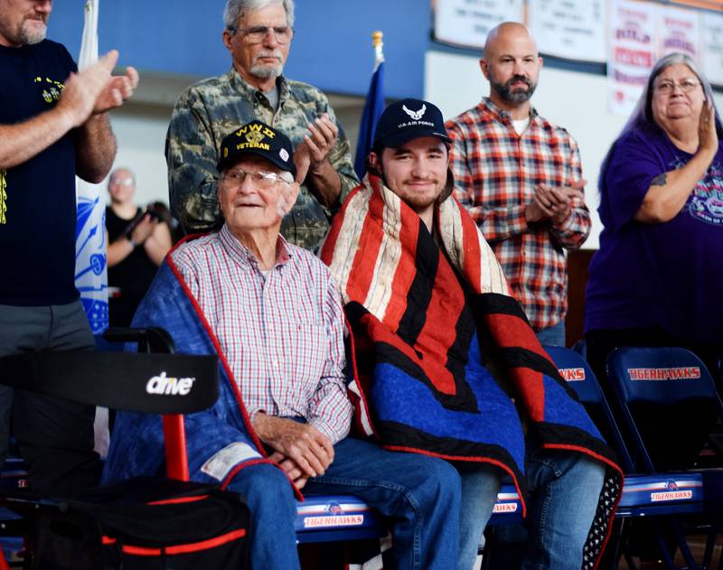 From left: Lawrence Opfer and his grandson Ethan Opfer get a standing ovation after receiving their Quilts of Valor simultaneously during a Veterans Day ceremony in Colfax-Mingo Jr./Sr. High School. Lawrence served the U.S. Navy Air Corps/U.S. Navy during World War II, and Ethan served the Iowa Air National Guard.