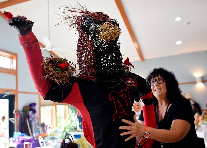 Christy McCormick, office manager at the Newton Arboretum & Botanical Gardens, shows off a scarecrow with a hand-woven cardinal head, which will be on display at the Fall Fest and Scarecrow Walk on Oct. 12 at the Newton Arboretum and Botanical Gardens.