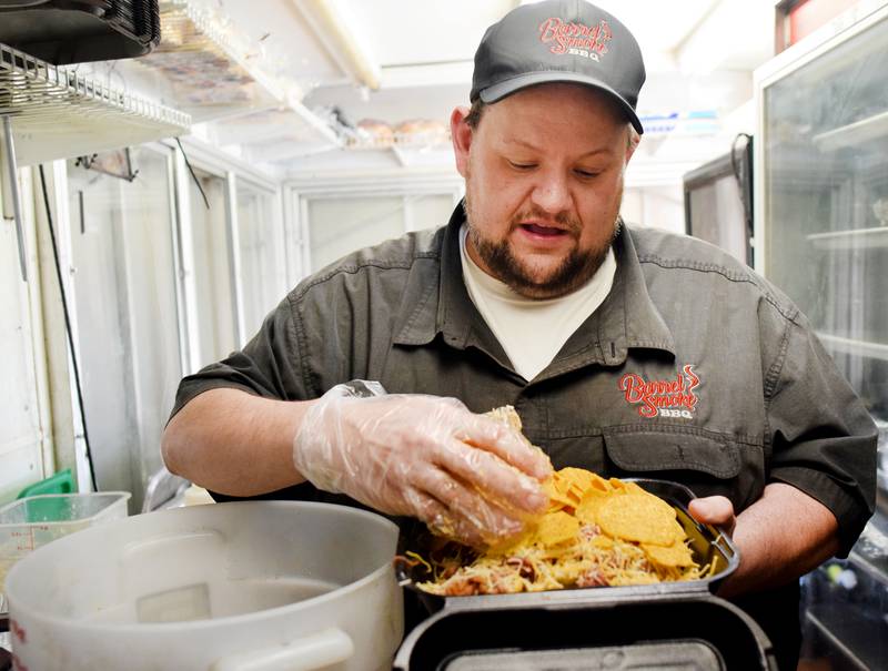 Eric White of Barrel Smoke BBQ & Catering prepares a serving barbecue pulled pork nachos during the Hy-Vee IndyCar Race Weekend's food truck challenge preview April 27 at Iowa Speedway in Newton.