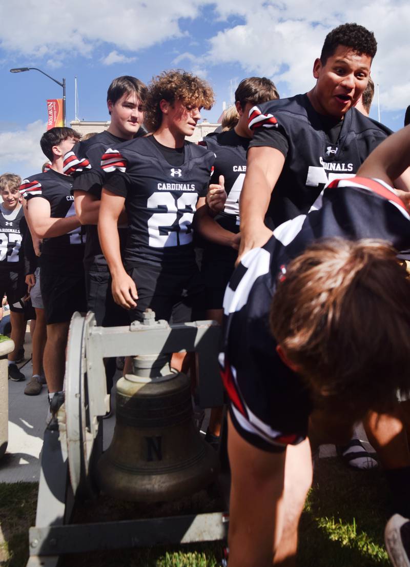 A football player reacts to his teammate stumbling over the victory bell during a pep rally Sept. 4 outside the Jasper County Courthouse in downtown Newton.
